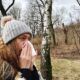 A woman wipes her nose as she suffers from fall cold season allergies.