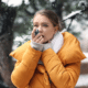While taking a walk in the snow, a woman uses her inhaler as she experiences asthma flare-ups in winter.